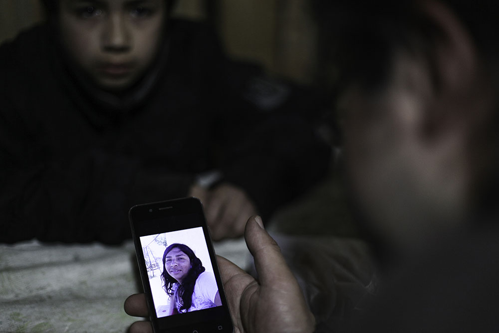 Ruben Collio junto a su hijo miran una fotografia de Macarena en su celular.©Ruta35r/Cristobal Saavedra